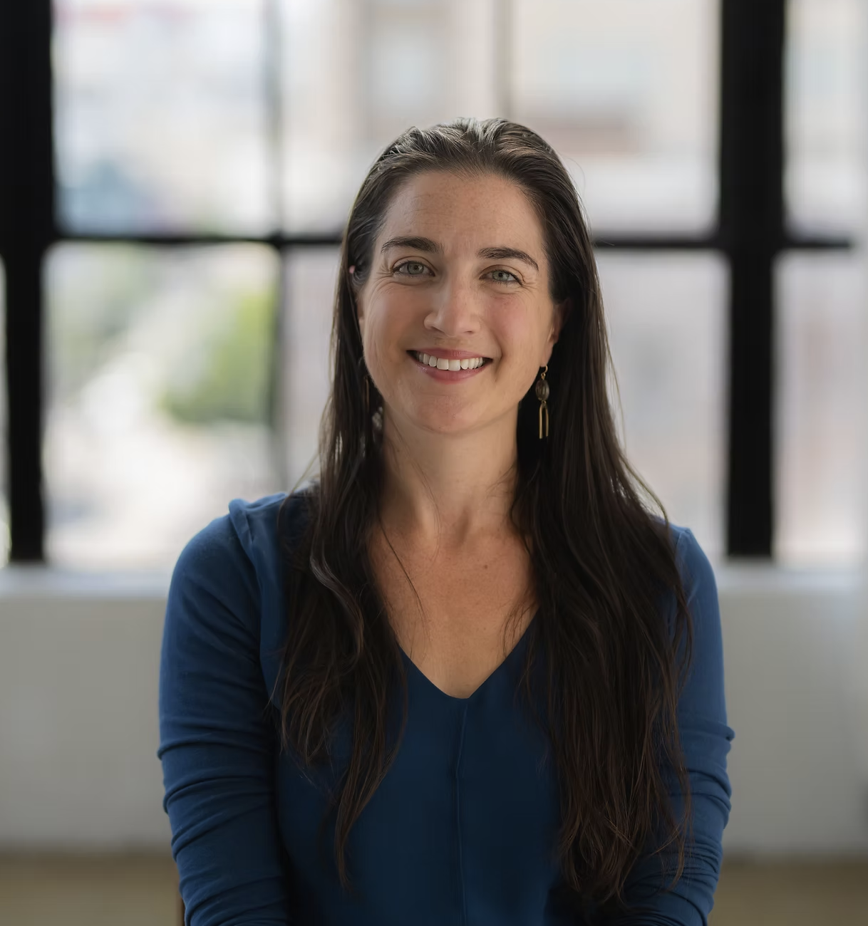 headshot of Julia in a room ith a navy blue shirt and long brown hair